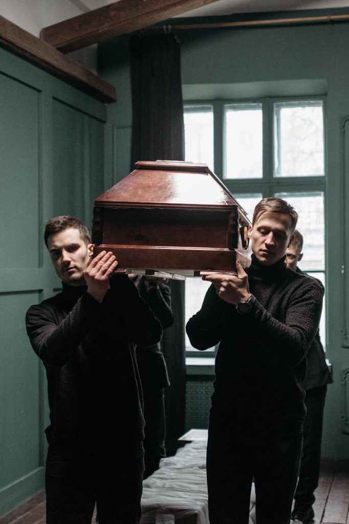 Karen Acres Celebrant A Group of Men in Black Clothing Carrying a Wooden Coffin